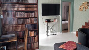 Un soggiorno con una libreria, una televisione, un divano e una scala.