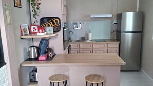 Una cucina con isola centrale, sgabelli da bar, frigorifero e lampadario.