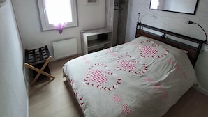 Una camera da letto con un letto, una finestra, un termosifone, una sedia, un armadio e uno specchio a parete.