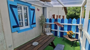 Una veranda coperta con una panca di legno, un tavolo e una recinzione blu.