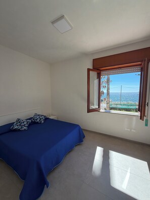 Um quarto com uma cama, uma janela com vista e uma luminária no teto.