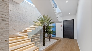 A modern interior with a staircase, a potted plant, and a door. - Villa Platinum by Homie (Calheta)
