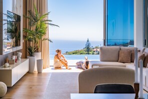 Ein modernes Wohnzimmer mit großem Fenster und Panoramablick, einer Couch und einem Couchtisch.
