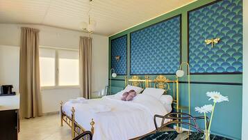 A bedroom with a bed, a desk, a chair, a vase with flowers, and a ceiling fan.