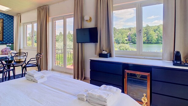 Een hotelkamer met een bed, een bureau, een televisie en uitzicht op een meer.