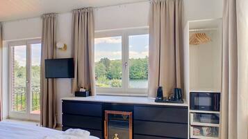Une chambre d’hôtel équipée d’un lit, d’une télévision, d’un bureau avec un ordinateur, d’une armoire et offrant une vue sur la verdure.