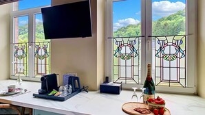 A kitchen with a TV, coffee maker, and breakfast items on the counter.