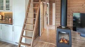 A modern kitchen with a wooden ladder, a wood-burning stove, and a TV. - 3 bedroom cozy home in åmli (Åmli)