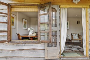 An open wooden door leading to a room with a dining table, chairs, and a vase of flowers. - East Cornworthy Cottage (Totnes)