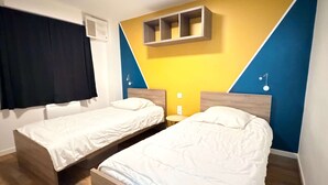 A room with two beds, a wall-mounted shelf, and a window with curtains. - Oléron Honeysuckle (Saint-Georges-d'Oléron)