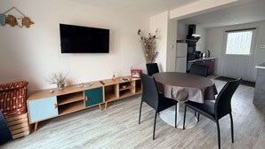 A modern living space with a dining area, a kitchen, and a TV mounted on the wall. - Oléron Honeysuckle (Saint-Georges-d'Oléron)