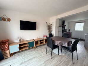 Ein modernes Wohnzimmer mit Essbereich, Küche und Wand-Fernseher.