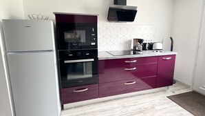 A compact kitchen with a refrigerator, oven, microwave, and a coffee maker on the counter. - Oléron Honeysuckle (Saint-Georges-d'Oléron)