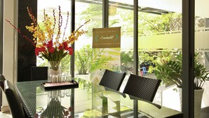 A glass table with chairs, a vase with flowers, and a sign indicating the apartment system. - CityHouse TERA Emerald (Ho Chi Minh City)