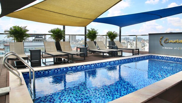 A rooftop pool with lounge chairs, a tiled pool, and a city view. - CityHouse TERA Emerald (Ho Chi Minh City)