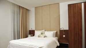 A hotel room with a bed, a headboard, a nightstand, a lamp, and a teddy bear. - CityHouse TERA Emerald (Ho Chi Minh City)