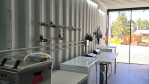 A kitchen with stainless steel appliances, a large refrigerator, and a sink. - Kenai River RV at Fish Camp + Processing (Soldotna)