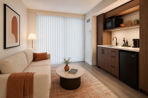 A modern living room with a sofa, coffee table, and a view of a kitchen area. - The Dominion Suites (Toronto)