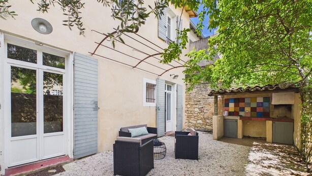 A courtyard with outdoor seating, a stone wall, and a tiled structure. - Village house (Rognes)