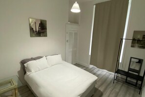 A bedroom with a bed, a bedside table, a wardrobe, and a window. - Property (Glasgow)