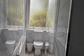 A bathroom with two toilets, a shower, and a window. - Property (Glasgow)