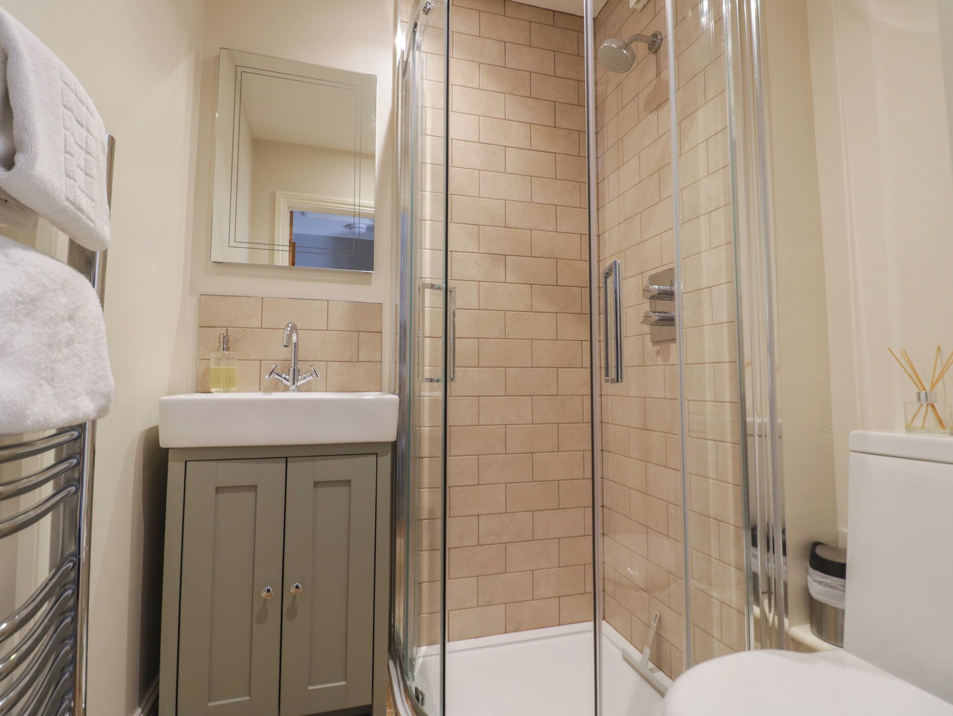 A bathroom with a glass-enclosed shower, a sink with a mirror above it, and a toilet.