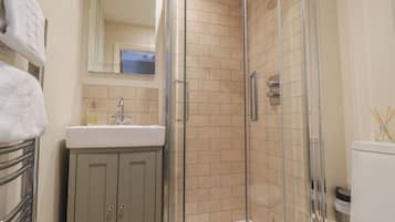 A bathroom with a glass-enclosed shower, a sink with a mirror above it, and a toilet.
