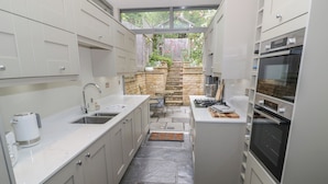 A compact kitchen with a stone backsplash, a built-in stove, and a sink.