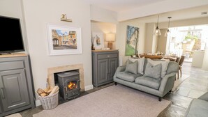 Una sala de estar con chimenea, sofá gris y televisor sobre un mueble.