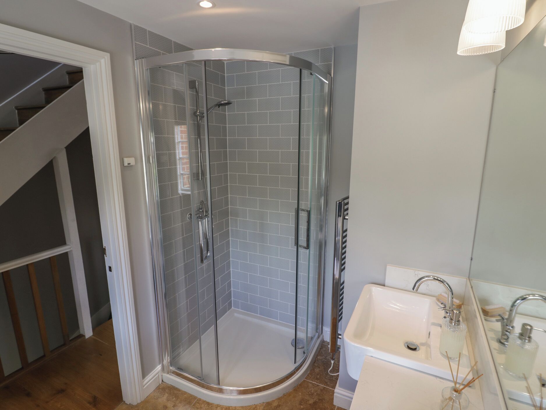 A modern bathroom with a glass-enclosed shower, a white sink, and a mirror.