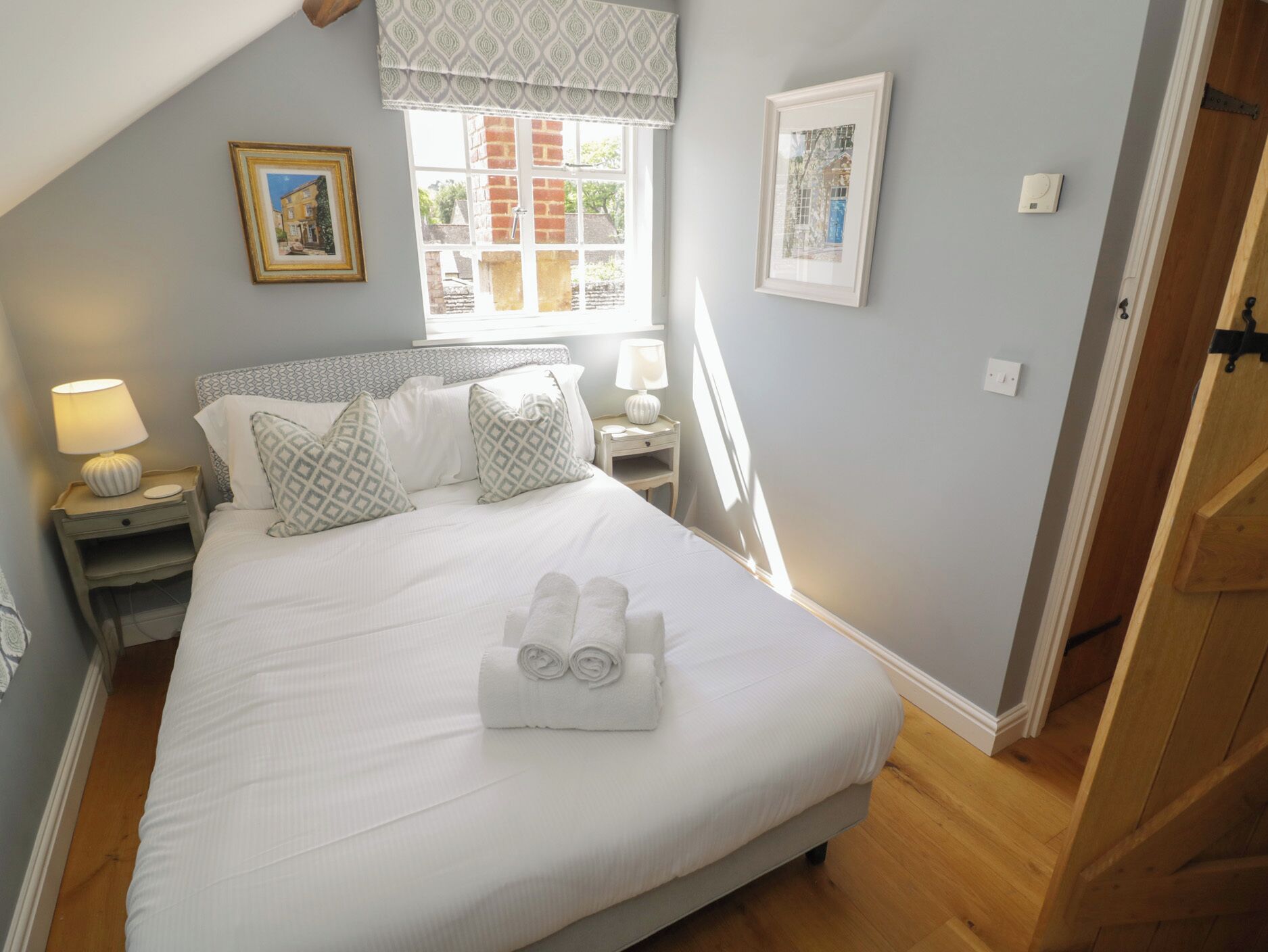 A bedroom with a bed, two bedside tables, a window, and a door.