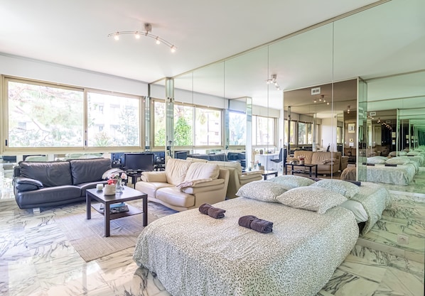 Amplia sala de estar con una cama grande, dos sofás, una mesa de centro y un televisor.