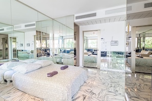 Una habitación de hotel moderna con una cama grande, un separador de vidrio y vistas al área de estar exterior.