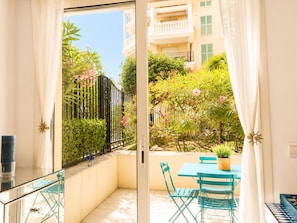 Ein Balkon mit Glastür, einem Tisch mit Stühlen und einem Blumentopf.