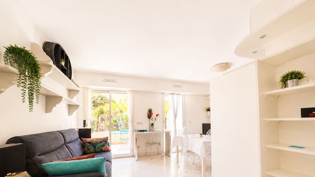 A modern living room with a sofa, a small table, and a dining area with chairs. - Beachfront Apartment in Menton (Menton)