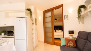 A compact living space with a kitchenette, a sofa, and a sliding door leading to a bedroom. - Beachfront Apartment in Menton (Menton)