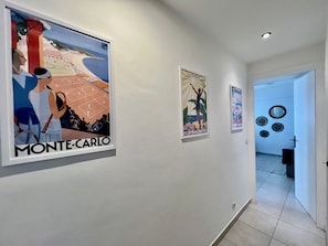 Un pasillo con tres carteles enmarcados en la pared, uno de los cuales está etiquetado 'MONTE-CARLO'.
