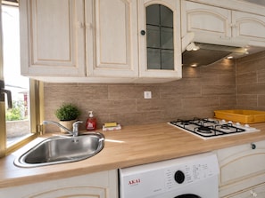 A kitchen with wooden cabinets, a stainless steel sink, a gas stove, and a dishwasher. - Small House Downtown Near Monaco (Beausoleil)