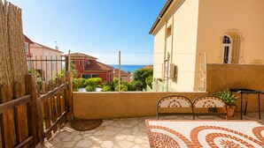 A terrace with a tiled floor, a wooden fence, and a view of the sea.