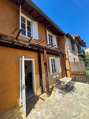 A two-story building with a stone patio, outdoor seating, and a wooden pergola. - Small House Downtown Near Monaco (Beausoleil)