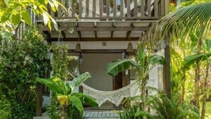 A wooden house with a balcony, surrounded by lush greenery. - Pousada Pais Tropical (Amontada)