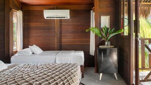 A wooden room with a bed, a small table, and an air conditioning unit. - Pousada Pais Tropical (Amontada)