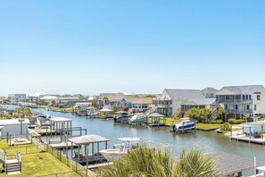A marina with boats docked, a clear sky, and residential buildings in the background. - Sunset Landing - 4 BR Home on Canal with Dock, Covered Porch, Pet Friendly! (Surf City)