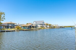 A waterfront property with multiple docked boats, a large house with a balcony, and a small building with a covered porch. - Sunset Landing - 4 BR home on Canal - covered porch, private dock, pet friendly! (Surf City)