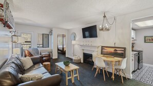 Ein modernes Wohnzimmer mit einer Ledersofa, einem Esstisch mit Stühlen, einem Kamin und einem an der Wand montierten Fernseher.