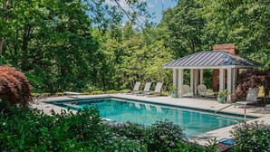 A swimming pool with lounge chairs, a gazebo, and lush greenery. - Kateri (Waynesboro)