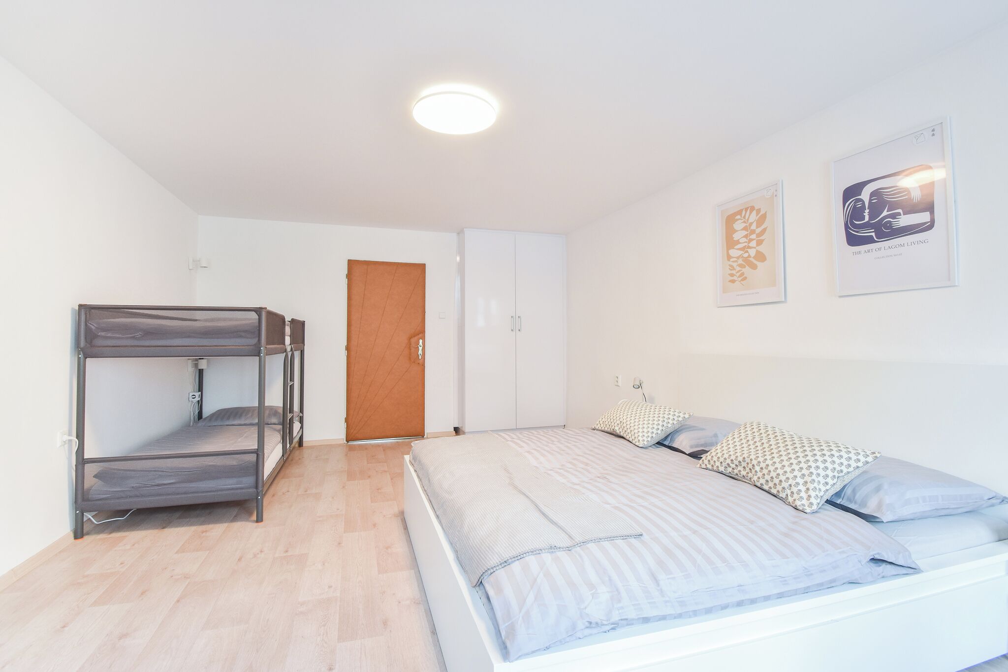 Een slaapkamer met stapelbedden, een garderobe, een deur en twee ingelijste kunstwerken.
