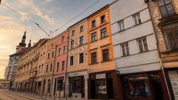 En rad med fler våningar höga byggnader, där bottenvåningen inrymmer butiker, inklusive en väl synlig butik med en skylt som visar texten ”ZLATNICTVI”.