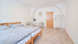 Une chambre avec deux lits, une petite table sur laquelle est posée une plante, une chaise et une armoire.