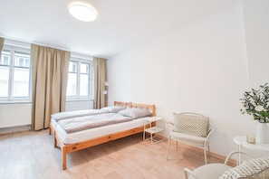 A bedroom with a wooden bed, a white chair, and a small table with a vase of flowers.